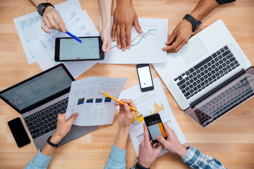 Business people using mobile phones and laptops, calculating and discussing charts and diagrams for financial report.jpeg