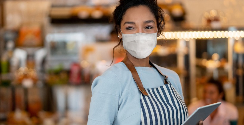 beautiful-waitress-working-at-a-restaurant-wearing-a-facemask-picture-id1225861935